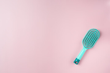 Blue hairbrush on a pink background. Copy space.