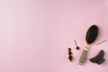 Hairbrush and hairpin on a pink background. Copy space