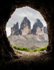 Vertical of an open cavern door against of rocky mountains in clouds