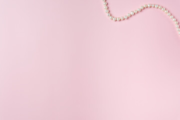 Pink background with string of pearls. Copy space