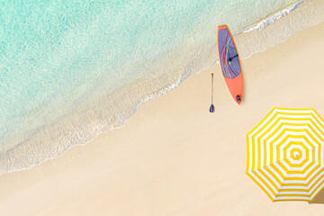 Top view of woman in bikini and hat lying near umbrella and sunbathes on tropical Seychelles sea sand beach with SUP board for surfing. Aerial, drone view - 732511225