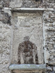 a window with a face carved into the stone wall behind it