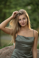Naklejka premium Portrait of a young beautiful blonde girl in a city summer park.
