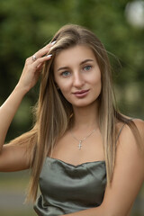 Naklejka premium Portrait of a young beautiful blonde girl in a city summer park.