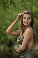 Fototapeta premium Portrait of a young beautiful blonde girl in a city summer park.