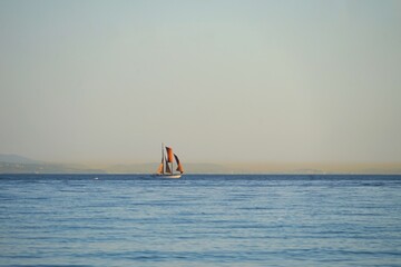 sailboat on the Atlantic Ocean seen from the beach in Andalusia, mountains of Morocco at the...