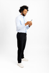 Friendly and positive African-American man in formal weaer using smartphone isolated, male employee checking emails, chatting online, shopping, using new mobile app, full length, vertical © Vadim Pastuh
