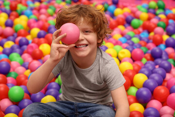 Happy little boy holding ball in play room