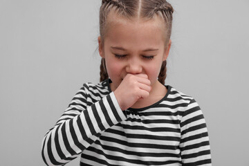 Sick girl coughing on gray background. Cold symptoms