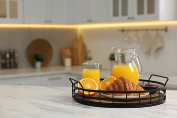 Breakfast served in kitchen. Tray with fresh croissant, jam and orange juice on white table, space for text
