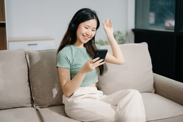 Young asian woman relax on comfortable couch at home texting messaging on smartphone and tablet smiling girl use cellphone  shopping online
