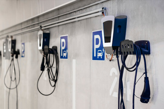 Electric Vehicle Charging Station in Private Garage Parking lot of Multifamily Building with Numbers and Control Panels. Underground Parking with Charge Points for Electro Car. - Powered by Adobe