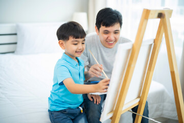 Young Asian Child and dad painting together on canvas and stand with smile of fun and happiness at home, relationship, activity with father and boy.