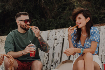 Group of cheerful friends enjoying food and drinks while relaxing near the beach cafe together