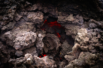 The quickly cooled lava crust creates an abstract. orange bright molten lava flowing on gray lava...