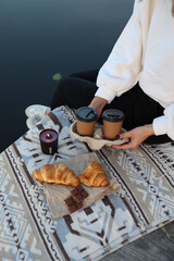 aesthetic photo. picnic on the pier with coffee and croissants, chocolate and candles