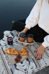 Fototapeta na wymiar aesthetic photo. picnic on the pier with coffee and croissants, chocolate and candles