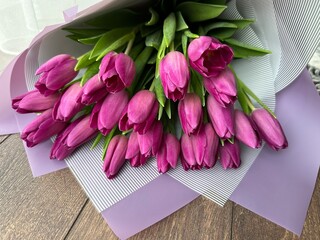 Spring flowers on a pink background, tulips. Bouquet of pink tulips in paper packaging.