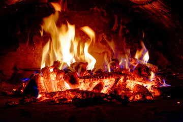 Bright flames rise energetically from burning wood logs.