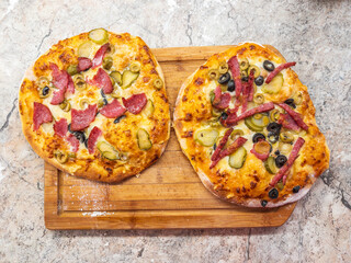 Two homemade pizzas with different toppings on a wooden board.