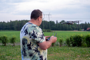 A man operating the drone by remote control on the meadow.