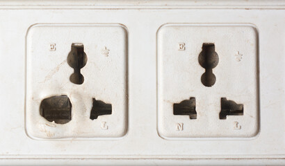 close-up of old electrical power sockets with melted and deformed plastic around the socket...