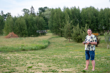 A man operating the drone by remote control on the meadow.