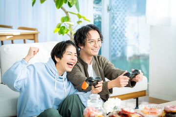 リビングでゲームをする若い日本人カップル