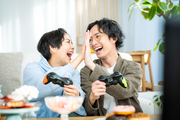 リビングでゲームをする若い日本人カップル