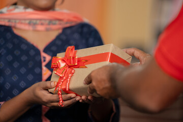 Close up shot of young girl hands receiving parcel or gift box from delivery person at home -...