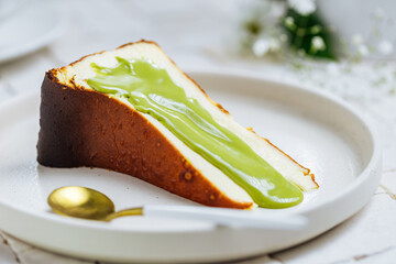 Popular Spanish dessert called San Sebastian cheesecake. It also known as burnt cheesecake. One piece of this dessert on white background with pistachio glaze on it.