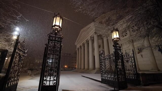Bucharest night snowfall full HD slow motion video 100fps. Amazing video with massive snow falling from sky during the night. View to Romanian Atheneum landmark building.