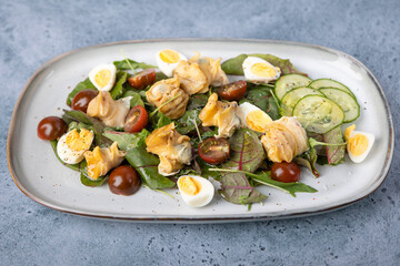 Warm salad with rapan (snails), tomatoes, cucumbers, leafy vegetables, quail eggs and olive oil. Traditional seafood salad. Close-up, selective focus.