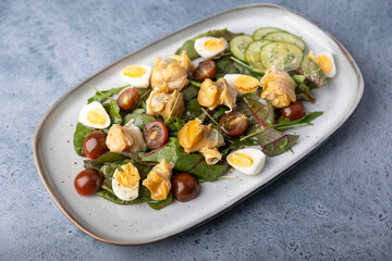 Warm salad with rapan (snails), tomatoes, cucumbers, leafy vegetables, quail eggs and olive oil. Traditional seafood salad. Close-up, selective focus.