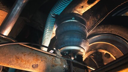 Warm light of the workshop, intricate air suspension system and tire details of a vehicle under maintenance.