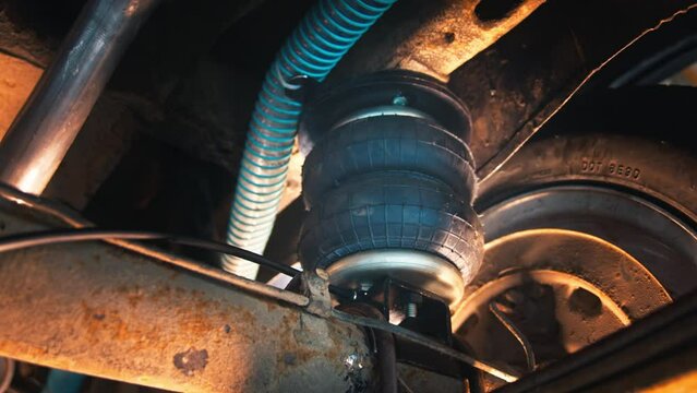 Warm light of the workshop, intricate air suspension system and tire details of a vehicle under maintenance.