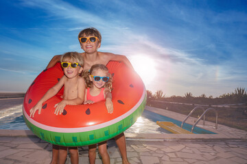 Happy siblings in sunglasses share float on sunset background