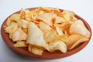 Cassava chips, in a wooden plate, isolated on white background