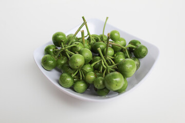 Fruit of Solanum nigrum, the European black nightshade or leunca, in a white bowl, isolated on white background