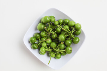 Fruit of Solanum nigrum, the European black nightshade or leunca, in a white bowl, isolated on white background, flat lay or top view