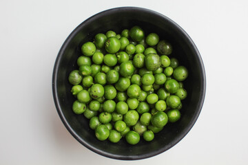 Fruit of Solanum nigrum, the European black nightshade or leunca, in a black bowl, isolated on white background, flat lay or top view