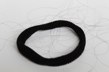 A black hair ties with strands of black hair. Hair loss or hair falling out or hair breakage