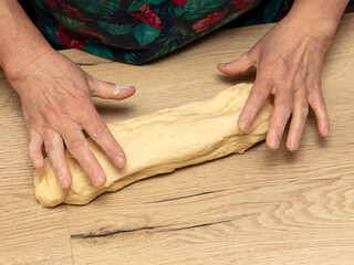A woman kneads dough with her hands