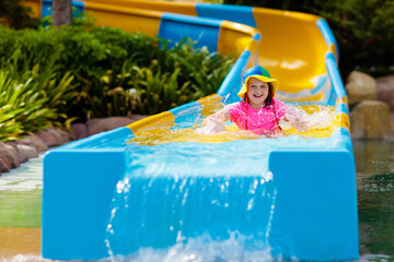 Kids on water slide in aqua park. Summer vacation