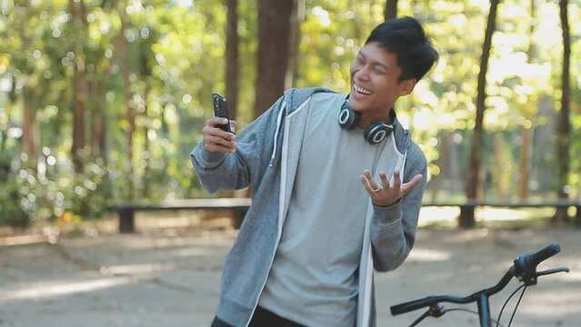 .A handsome young man goes to the city with his bike. He is sitting on a bike and sending text message on the smartphone.