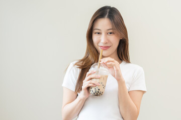 Beverage and food concept, Happy asian young woman hand holding plastic cup, glass of drink bubble, pearl milk tea with straw, cute girl drinking ice cold tea with tapioca boba ball popular in Taiwan.