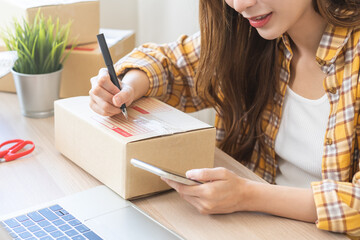 Online seller store, owner small business entrepreneur asian young woman packing product in box,...