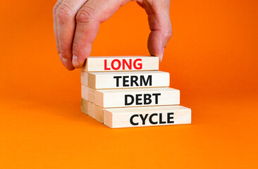 Long term debt cycle symbol. Concept words Long term debt cycle on beautiful wooden block. Beautiful orange table orange background. Businessman hand. Business Long term debt cycle concept. Copy space
