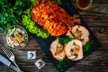 Stuffed turkey breast roulade with dried apricots and cranberries on wooden table
