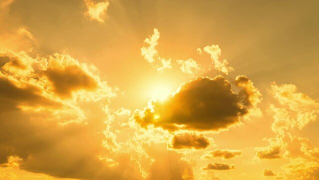 Beautiful heavy sunny cloudscape. Timelapse of golden fluffy clouds and sun set moving on the sky with sun rays and lens flare. Epic tropical storm sunset time lapse. Yellow red background.